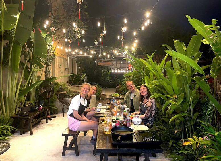 An outdoor dining area with string lights, tables, and chairs surrounded by tropical plants. 5