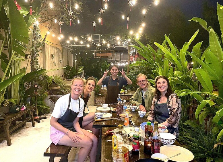 A group of people seated at an outdoor table with various food items and condiments. 4