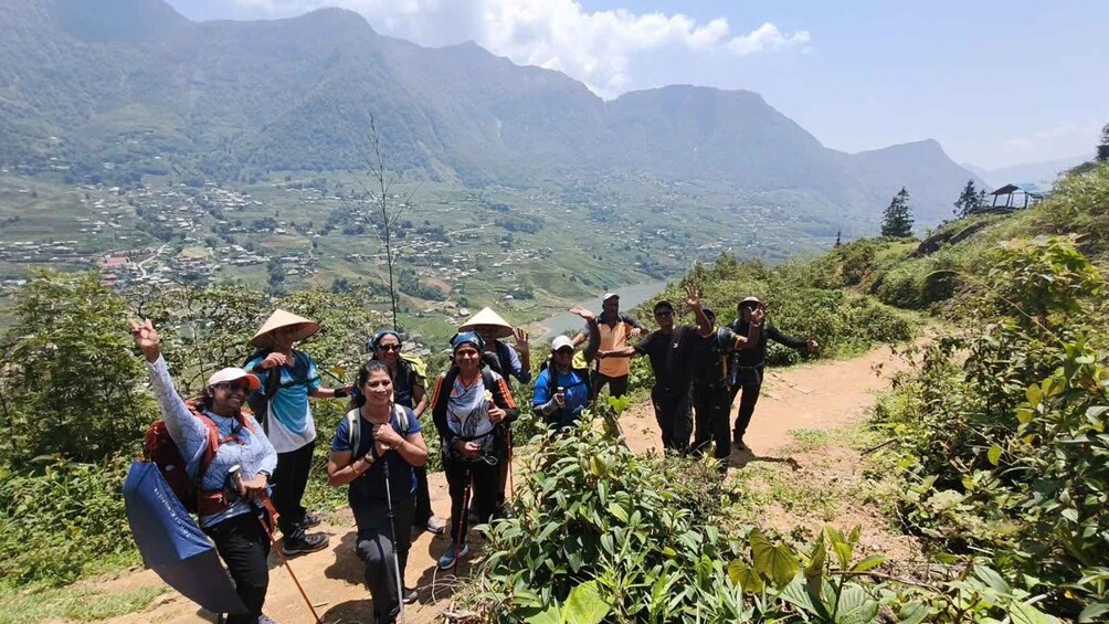A group of hikers on a mountain trail with a scenic view of a valley and mountains in the background. 5