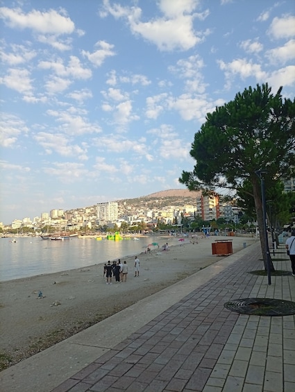 A beach with people, a cityscape, and a clear sky. 4