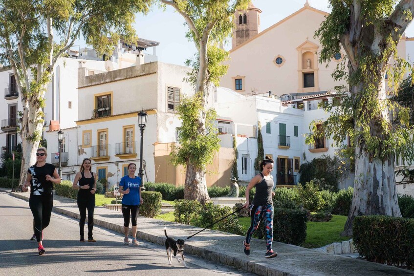 A group of people jogging on a tree-lined street with historic buildings in the background. 3
