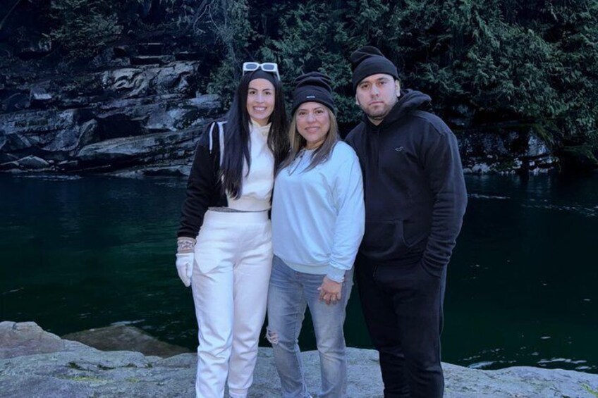 Three people standing by a body of water with a rocky cliff in the background. 2