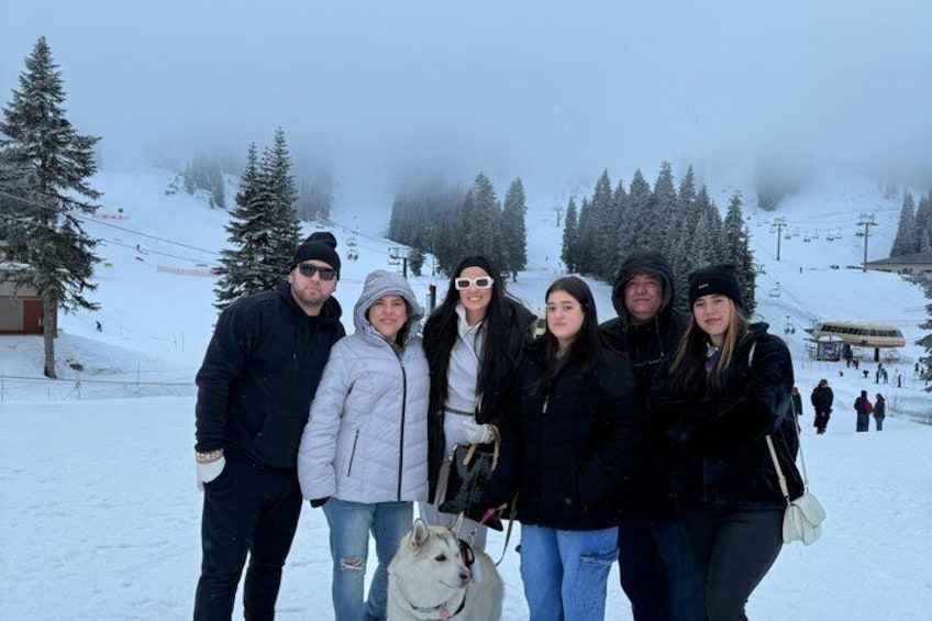 A group of people standing on a snowy slope with ski lifts in the background. 4