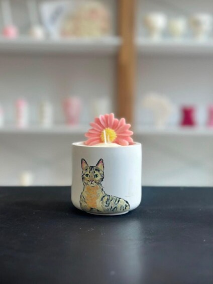A white mug with a cat illustration and a pink flower on top. 3