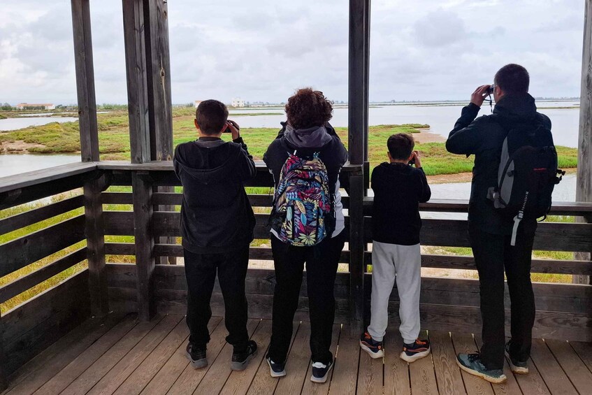 A group of people standing on a wooden deck overlooking a body of water. 2