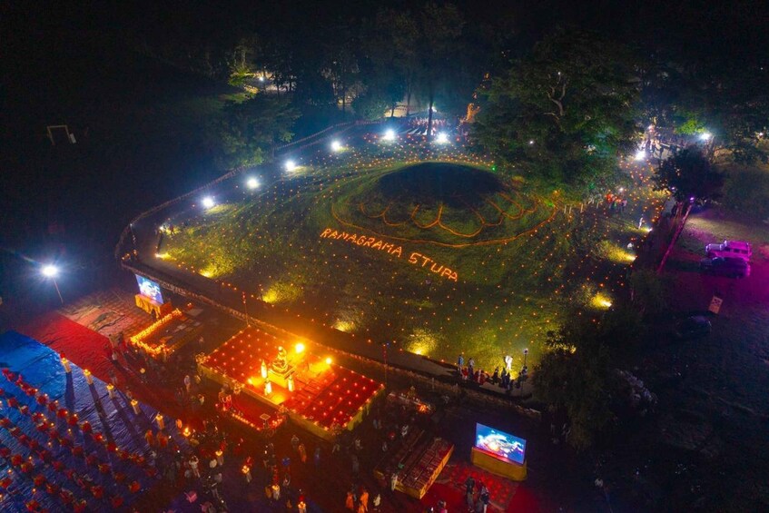 A large outdoor stadium with a circular pattern on the field, surrounded by trees and lights. 5