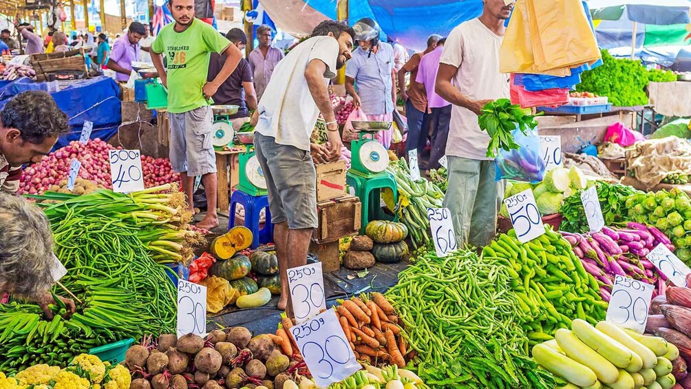A bustling outdoor market with various fresh vegetables on display, including green beans, carrots, and leafy greens. 4