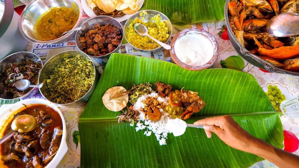 A variety of dishes served on a banana leaf with a spoon. 3