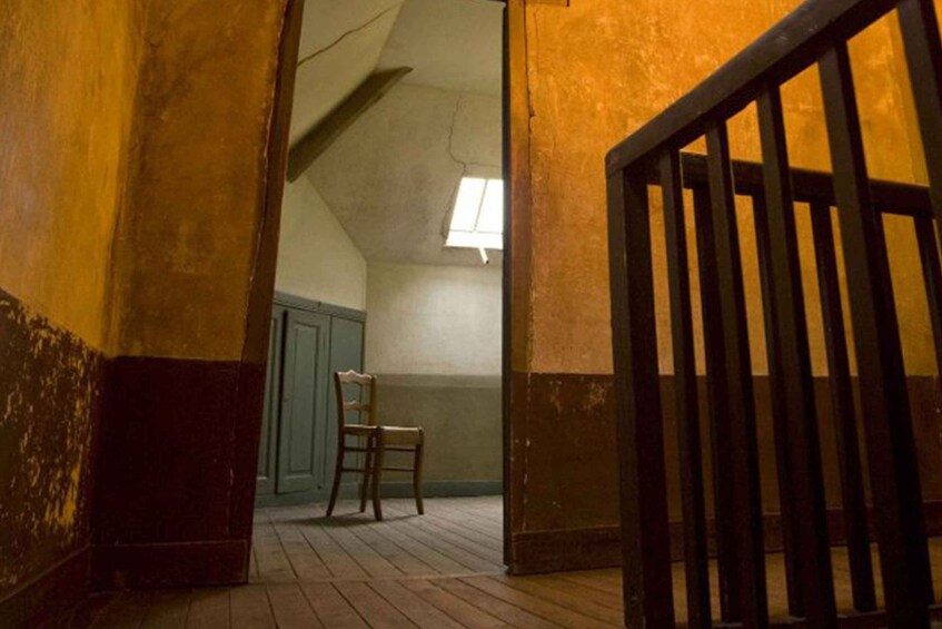 A wooden staircase with a black railing leading to a room with a chair and a window. 2