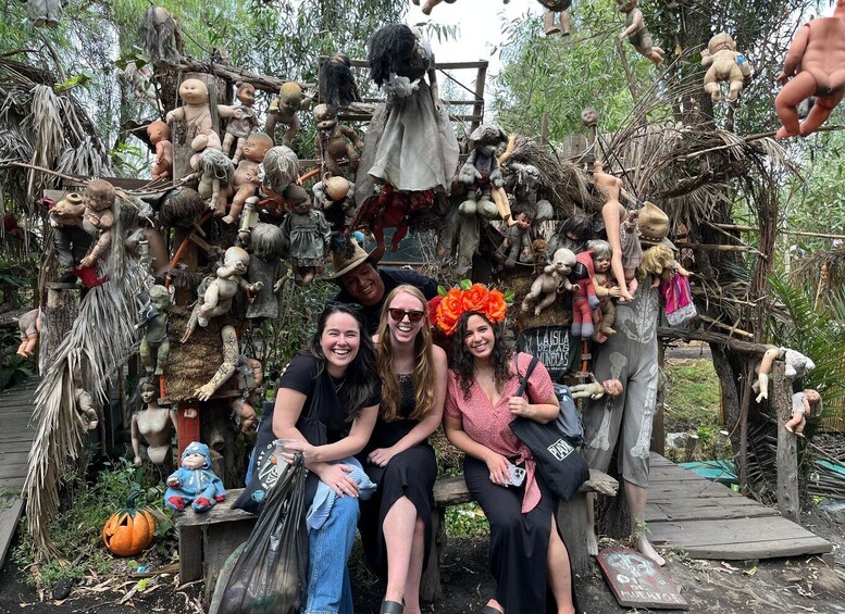 A group of people posing in front of a cluttered display of dolls and figures. 1