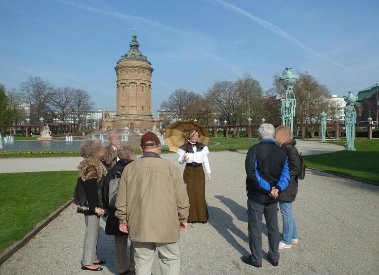A group of people standing on a paved path in a park with a historic tower in the background. 2