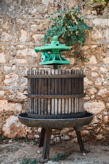 A rustic outdoor grill with a green top, set against a stone wall backdrop. 2