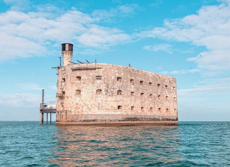 A large, historic stone building with a cylindrical tower, situated on a pier extending into the water. 3