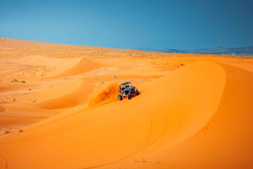A quad bike navigating a sand dune in a desert landscape. 2