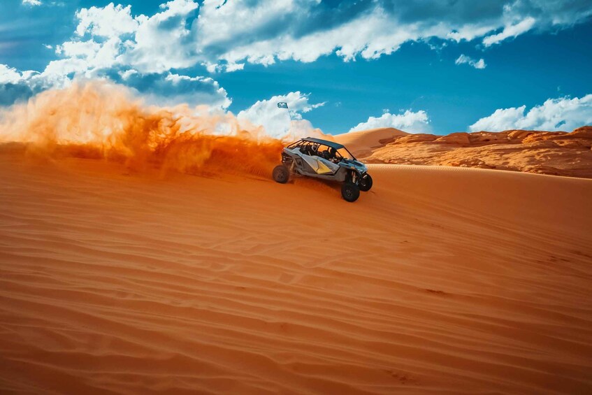 A vehicle driving through a desert with sand being kicked up behind it. 1