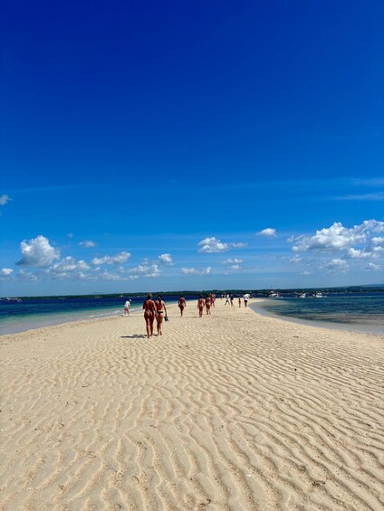 A beach with people walking on the sand and boats in the water. 5