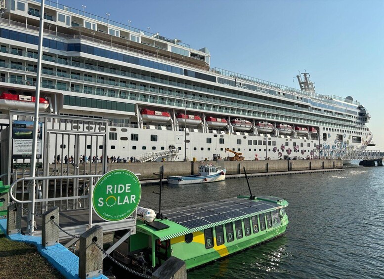 A cruise ship docked at a port with a green and yellow solar-powered boat named 'Ridesolar' in the foreground. 4