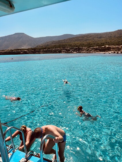 A clear blue sea with swimmers and a boat. 5