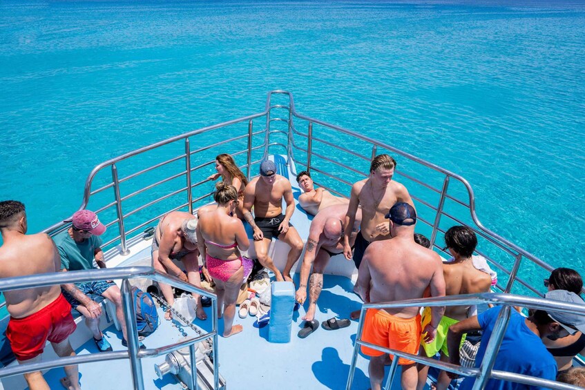 A group of people on a boat with a clear blue sea in the background. 2