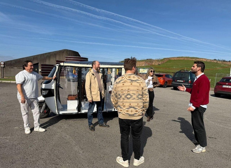 A group of people standing around a small trailer in a parking lot with a clear sky and a hilly landscape in the background. 3