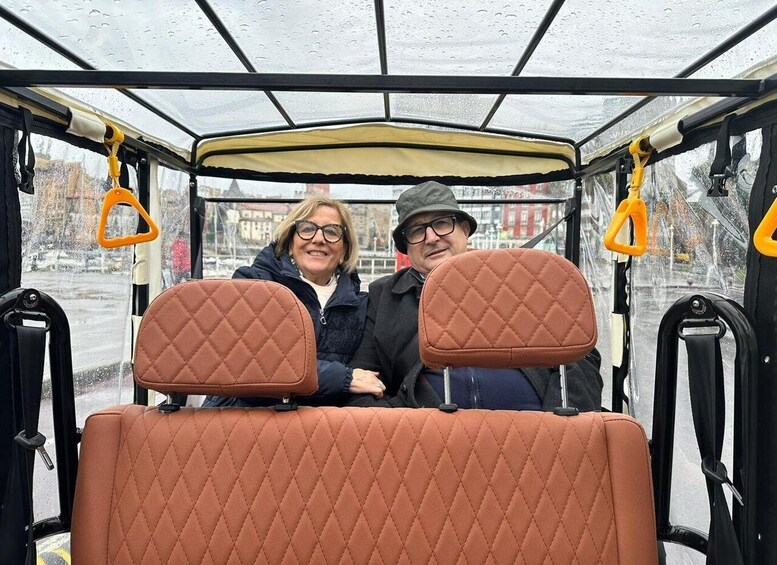A vintage tram with two passengers, a man and a woman, seated in the front. 4