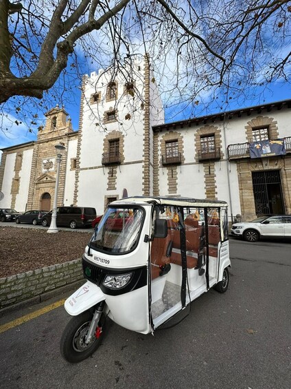 A white three-wheeled vehicle parked in front of a historic building with a clock tower. 5