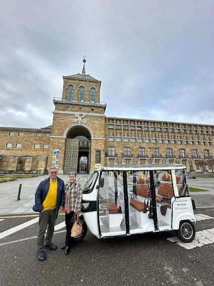 A building with a clock tower and a white vehicle with brown seats parked in front. 2