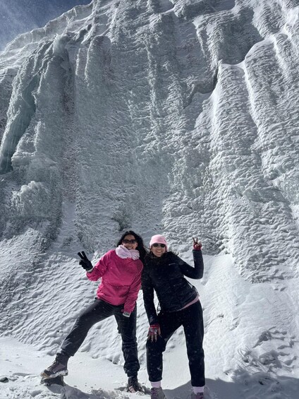 Two people standing in front of a large ice formation. 1