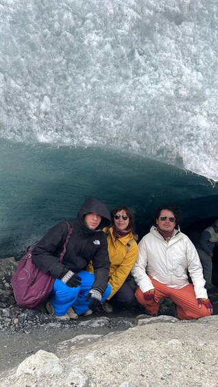 Three people sitting by a glacier. 5