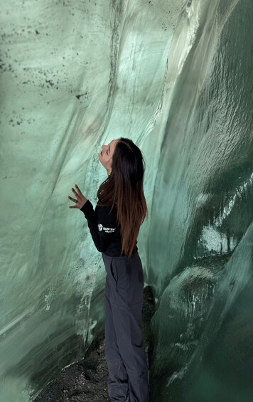 A person standing inside a cave with ice formations. 3