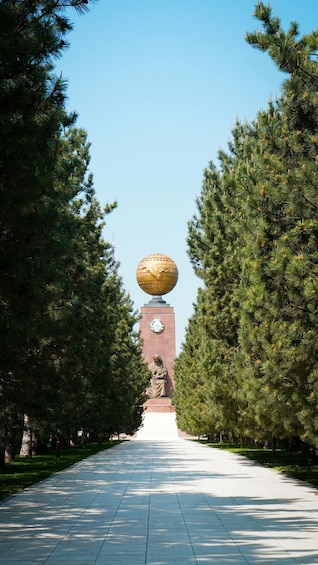 A pathway lined with trees leading to a building with a large golden sphere on top. 5