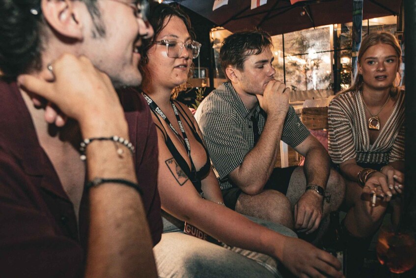 A group of people sitting closely together, engaged in conversation. 3