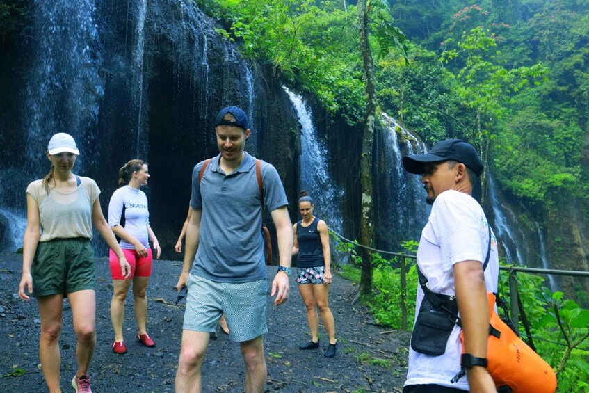 A group of people walking on a path with a waterfall in the background. 2