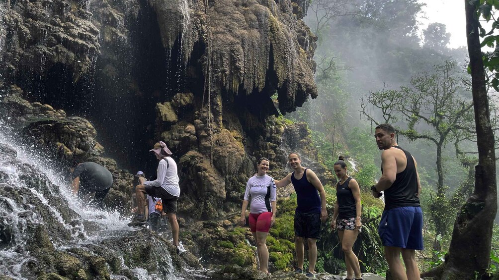 A group of people standing on a rocky waterfall. 4