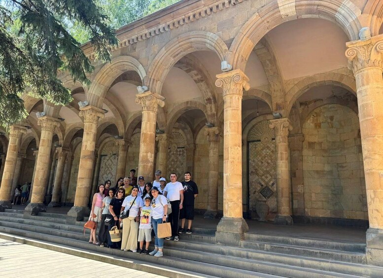 A group of people standing in front of a historical building with arches and columns. 3