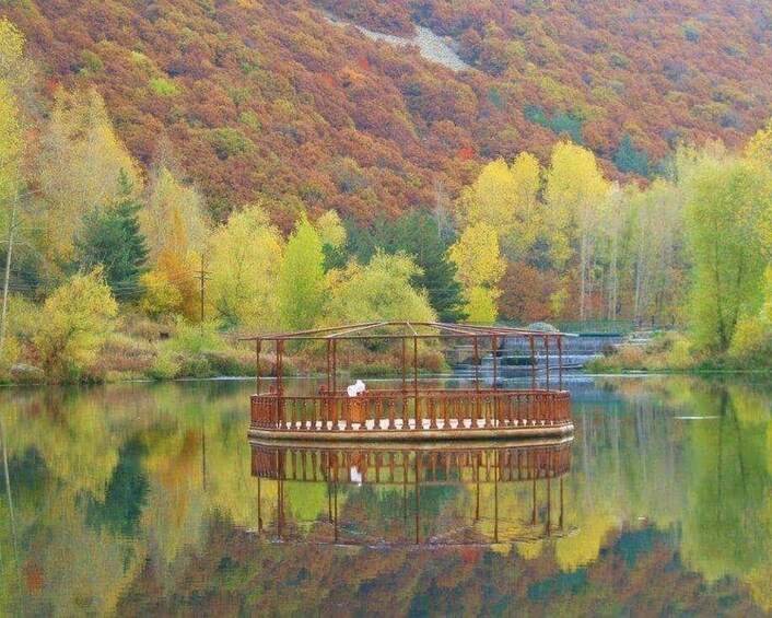 A wooden boat on a calm lake surrounded by autumn-colored trees. 4