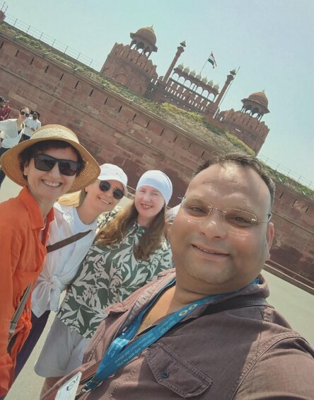 A group of people standing in front of a historical fort with a large gate and domed towers. 2