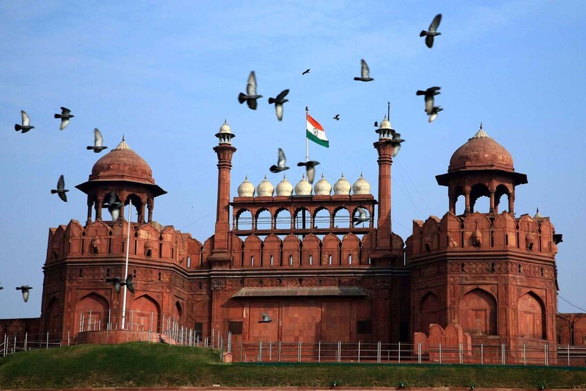A large red sandstone building with domes and minarets, featuring an Indian flag. 5