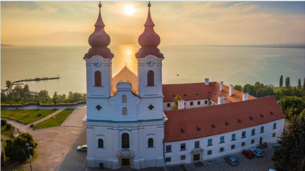 A church with two towers and a red roof, surrounded by a body of water and greenery. 4