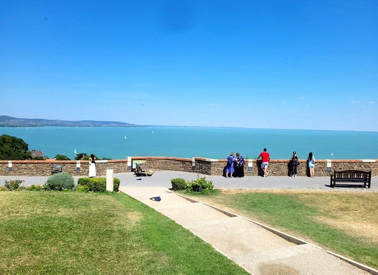 A coastal overlook with people enjoying the view, a stone wall, and a grassy area. 5