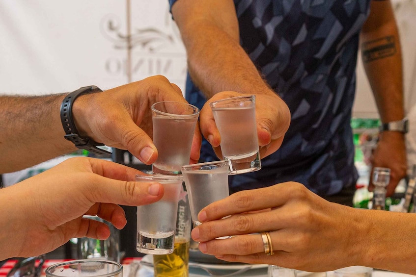 A group of people toasting with shot glasses filled with a clear liquid. 1
