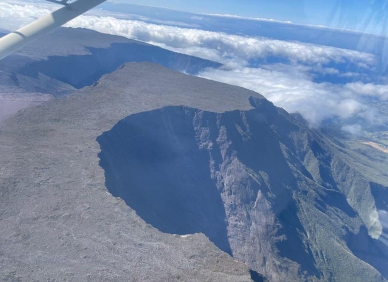 A volcanic crater surrounded by rugged terrain and clouds. 3