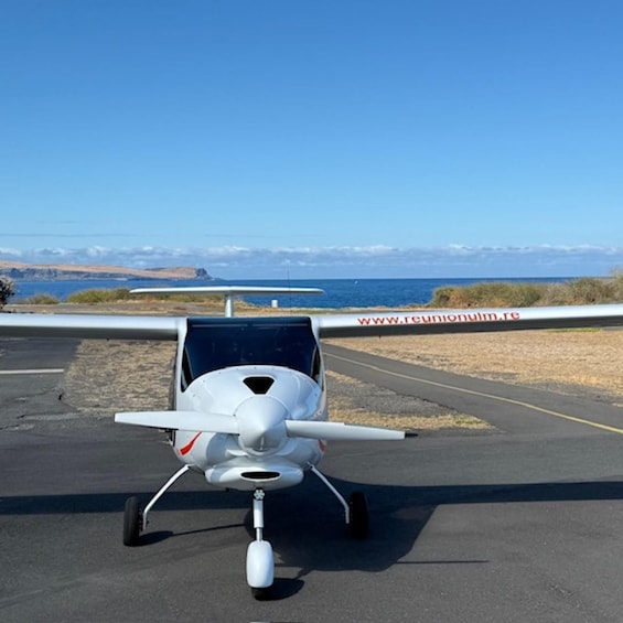 A small white aircraft on a tarmac with a clear sky and distant mountains. 4