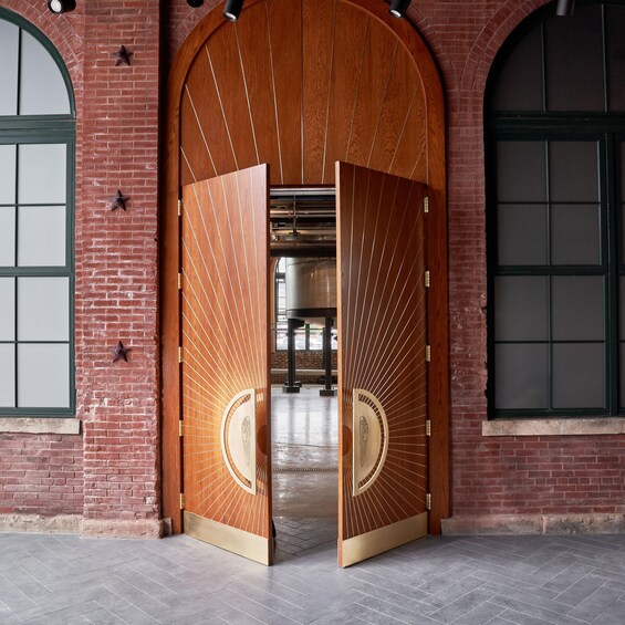 A large wooden door with a sunburst design, set in a brick building with arched windows. 4