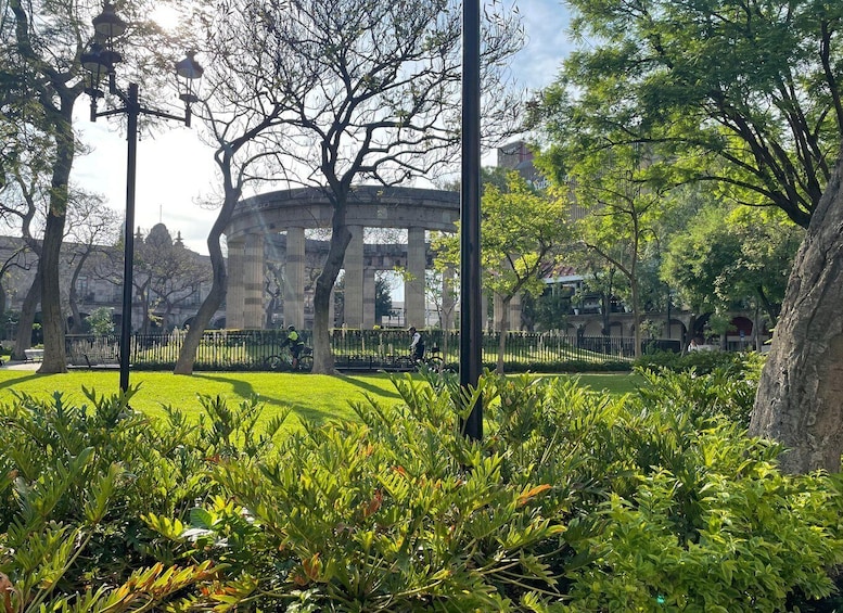 A park with a large stone archway, lush greenery, and a well-maintained lawn. 3