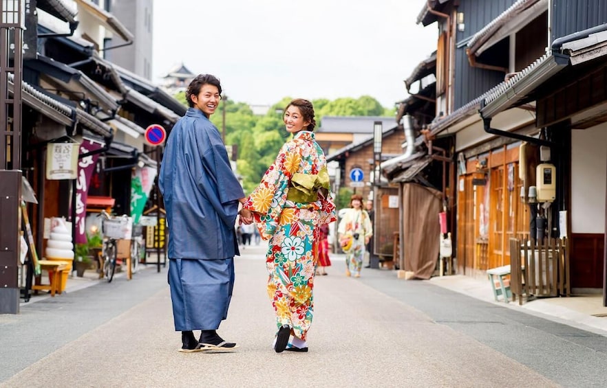 A traditional Japanese street with wooden buildings and a couple in kimonos walking down the path. 5
