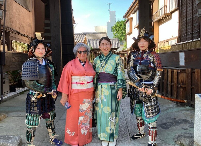 Four people in traditional Japanese attire standing in an alleyway with wooden buildings. 3