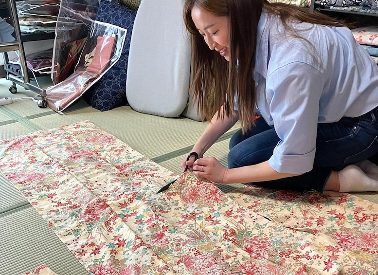 A person cutting a floral patterned fabric on a tatami mat. 1