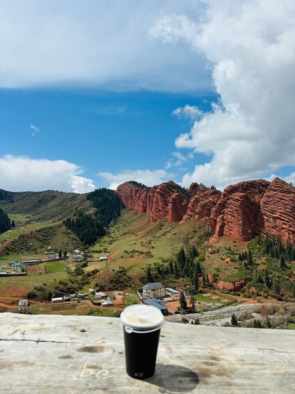 A black disposable cup on a table with a scenic view of red rock formations and a clear blue sky. 1
