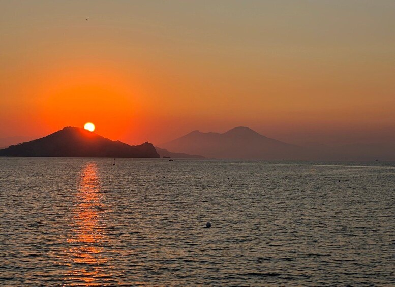 A sunset over a calm sea with a silhouette of a mountain and a small island. 5